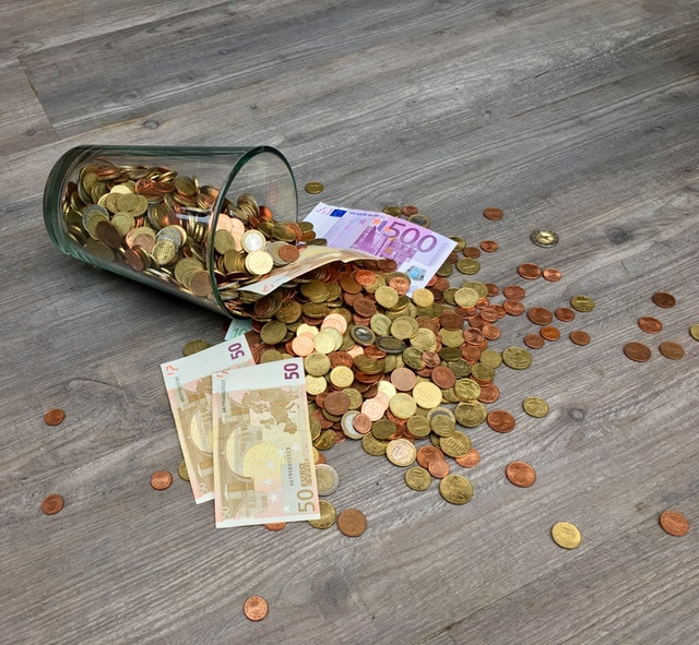sklenice s rozsypanými penězi.jpg